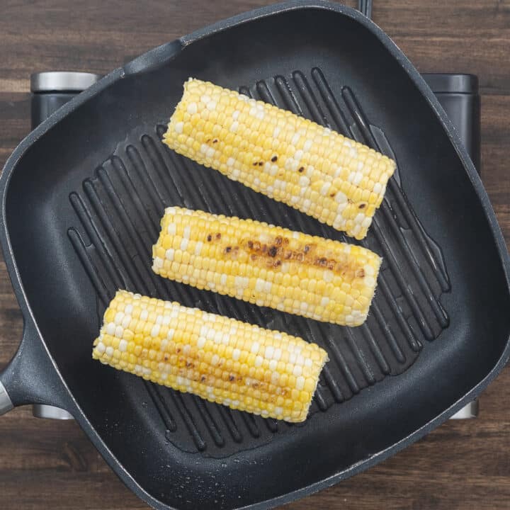 Corn grilling on the pan, showing a nice char and golden spots.