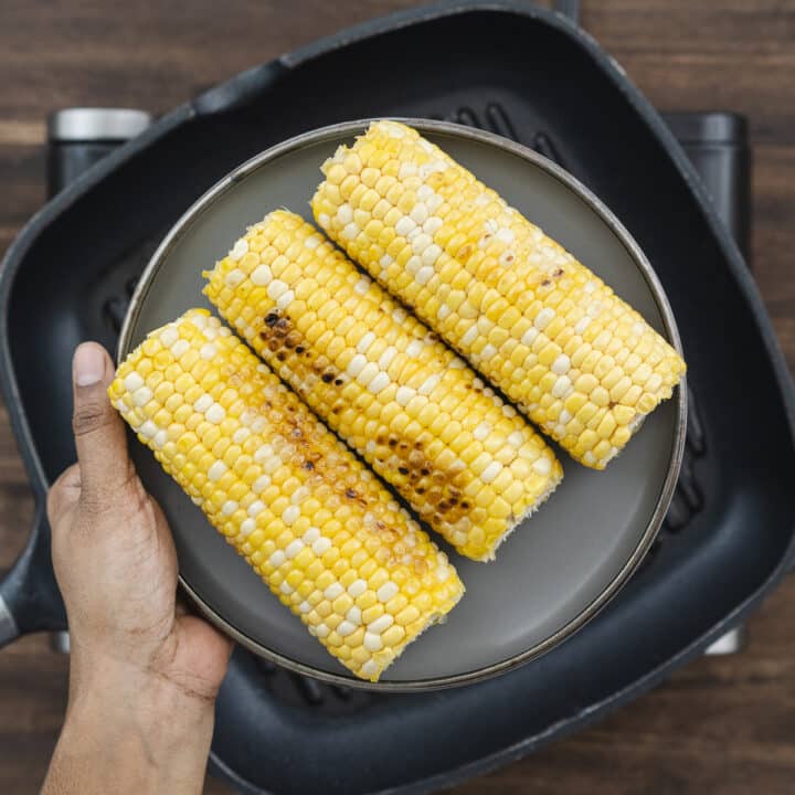 A gray plate with freshly grilled corn arranged neatly.