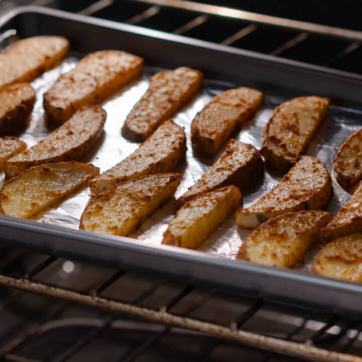 Potato wedges baking in the oven, starting to turn golden brown.