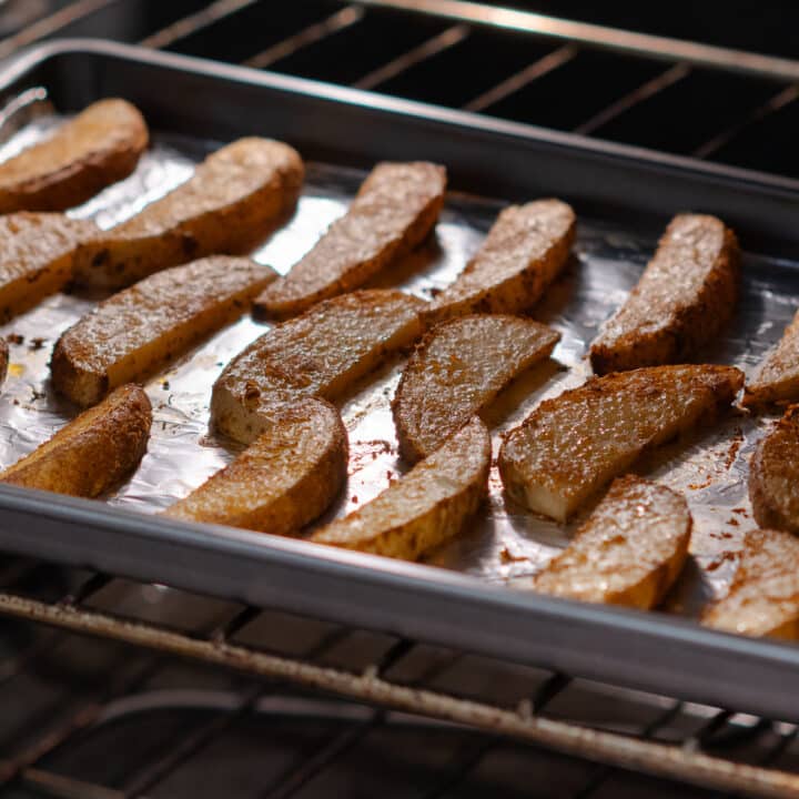 Crispy potato wedges in the oven, flipped halfway through baking for even cooking.