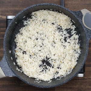 Pan with rice added to the sautéed garlic, ready for cooking.