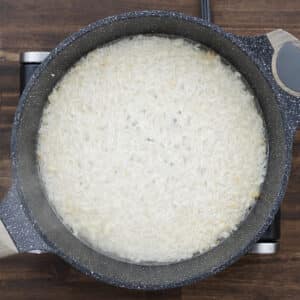 Pan with rice boiling in water.