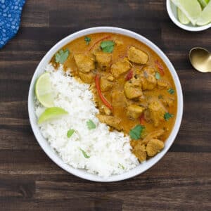 A bowl of coconut chicken curry served alongside a side of steamed jasmine rice.