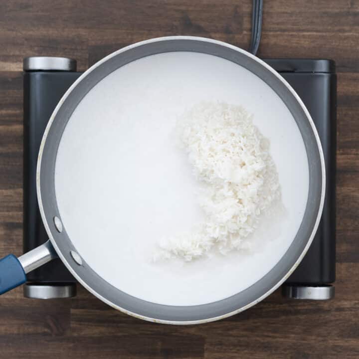 A pan filled with rice and coconut milk, prepared for simmering.