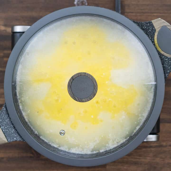 A pan with polenta cooking in water, lid closed.