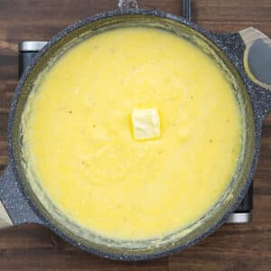 A pan with creamy polenta, butter added to it.
