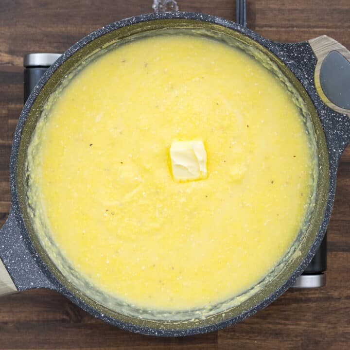 A pan with creamy polenta, butter added to it.