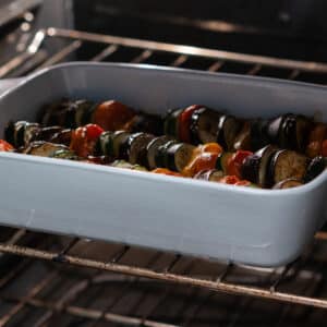 A baking dish in the oven with ratatouille veggies in tomato sauce, uncovered for final baking.