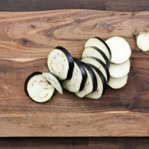 A cutting board with eggplant slices cut into circular shapes.