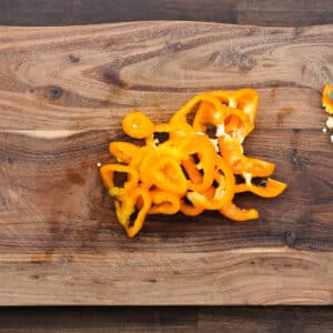 A cutting board with orange bell pepper sliced into rings.