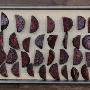 Seasoned beets arranged on a baking tray lined with parchment paper.