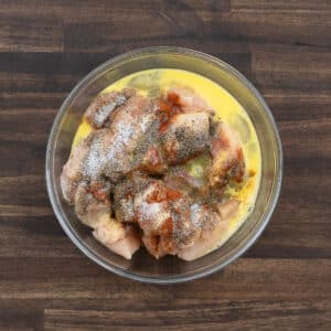 A bowl with boneless chicken and marination ingredients.