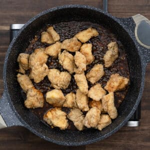 A pan with sesame sauce and fried chicken combined.