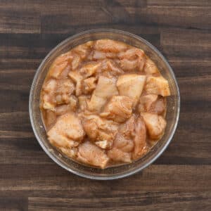 A bowl with chicken marinated in spices and eggs.