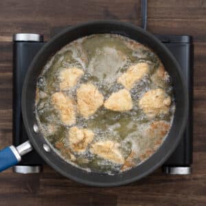 A pan with flour-coated chicken fried to golden brown and crispy.