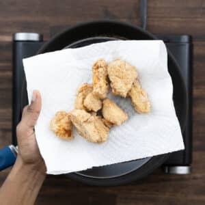 A plate with fried chicken on a paper-lined surface.