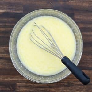 A bowl filled with wet ingredients, including eggs, milk, and fats, mixed together to create the base for the cornbread batter.