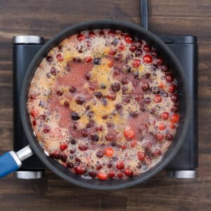 Cranberries bursting in the heated sugar syrup, releasing their juices and creating a thick sauce.