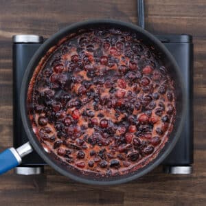 A pan with cranberry sauce cooked to a slightly thick consistency, showing a rich red color.