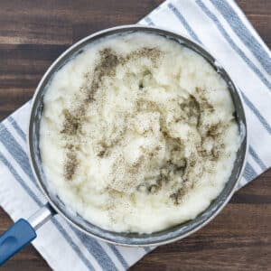 A pot with mashed potatoes seasoned with black pepper.