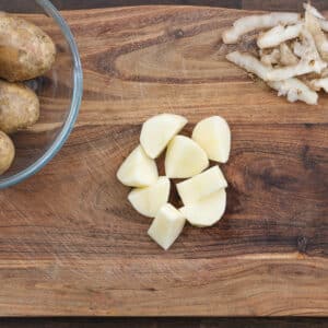 A cutting board with evenly sliced potatoes.