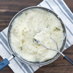 Creamy mashed potatoes in a pot, mixed with a rich butter and milk mixture.