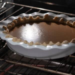 Pumpkin pie baking in the oven, with the filling starting to set.