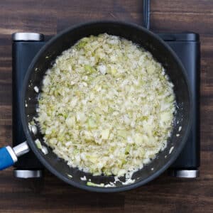 A pan with the sautéed aromatics in butter, seasoned with salt and black pepper.