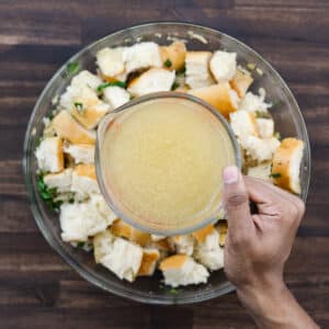 Pouring chicken broth into the bread mixture.