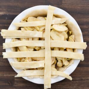 Partially woven lattice strips arranged neatly over the apple filling.