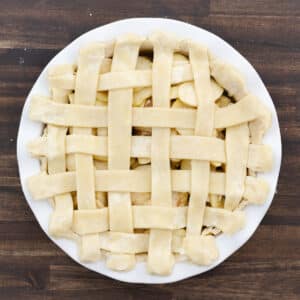 A pie dish with the lattice crust edges sealed neatly against the bottom crust.