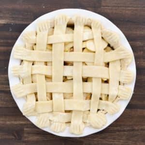 A pie dish with lattice top crust edges crimped with a fork for a polished finish.