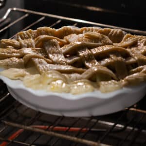 An apple pie baking in the oven, starting to turn golden brown on the edges.