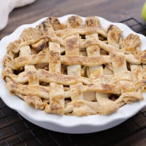 A perfectly golden brown apple pie served in a white pie dish, ready to be enjoyed.
