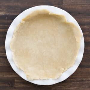 A pie dish with a neatly placed bottom crust, placed in evenly.