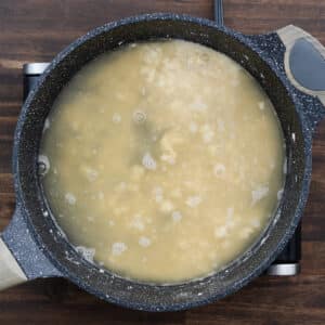 A pan with roux and chicken broth combined, ready to be whisked.
