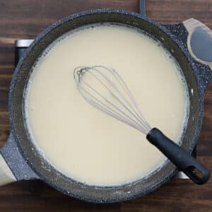 A pan with a smooth mixture of whisked roux and chicken broth.
