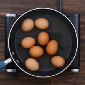 A pan with eggs covered in water, ready to be boiled.