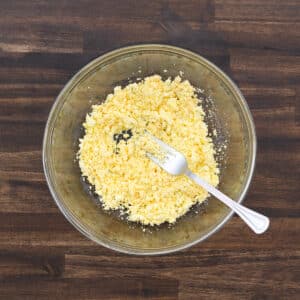 A bowl with mashed egg yolks, smoothly blended with a fork.
