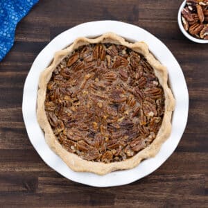 A perfectly baked pecan pie served on a white pie dish, ready to enjoy.