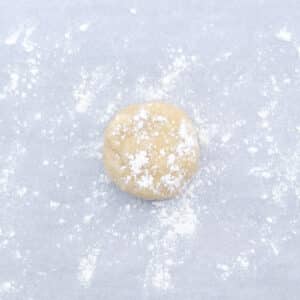 Chilled pie dough disc on parchment paper dusted with flour, ready to be rolled out.