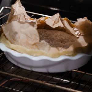 Pie crust prebaking inside the oven with pie weights.