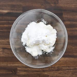 A bowl of powdered sugar and cream cheese ready for blending.
