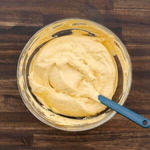 A bowl of the finished pumpkin dip, with a spatula used for mixing placed inside.