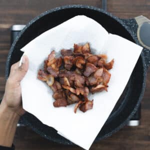 Crispy and browned bacon placed on a paper towel-lined plate.