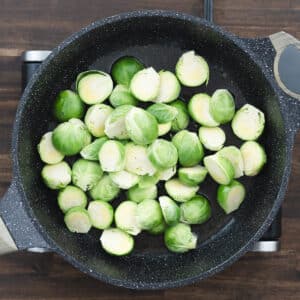 Halved Brussels sprouts added to the pan, soaking up the flavorful bacon drippings.