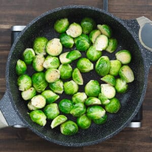 Brussels sprouts evenly coated in bacon drippings, ready to cook further.