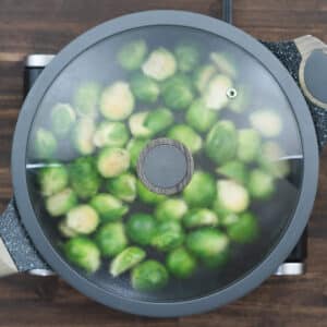 Brussels sprouts covered with a lid, steaming slightly to make tender insides.