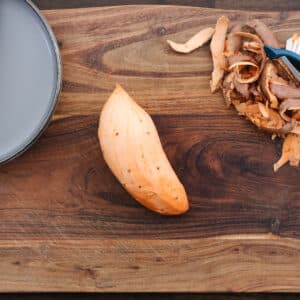 Peeled sweet potatoes placed on a cutting board, ready for preparation.