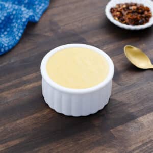 Cheddar cheese sauce served in a white bowl, rich and velvety, ready to enjoy.